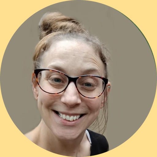 Amanda Pigman, smiling, wearing glasses with her hair tied up