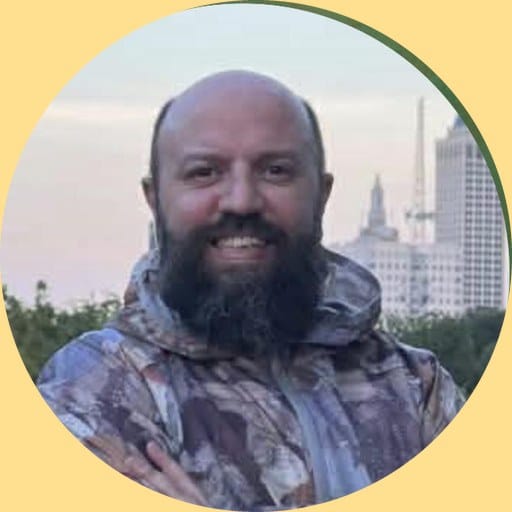 Andrew Nutter, smiling, in a patterned jacket with the Tulsa skyline at dusk behind him